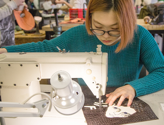 student bending over a sewing machine