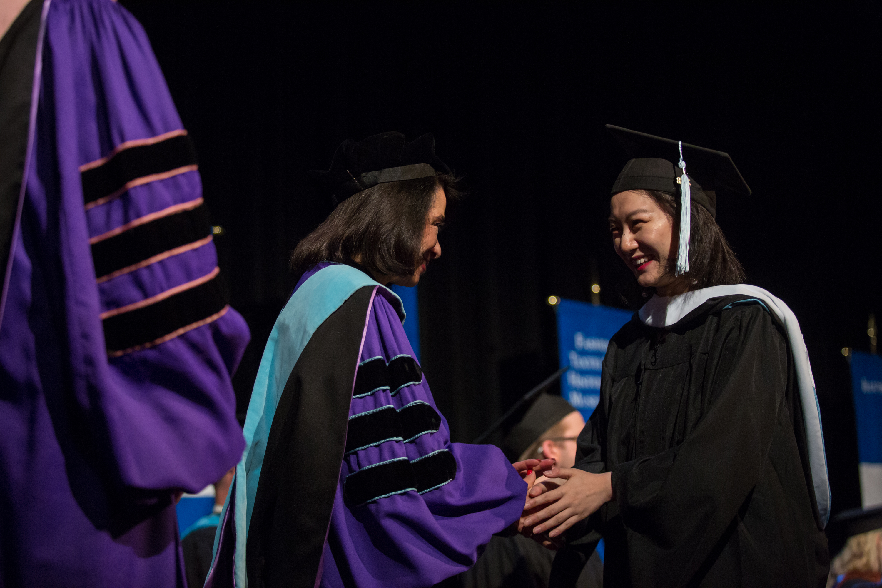 President Brown shaking hand of master's graduate in cap and gown